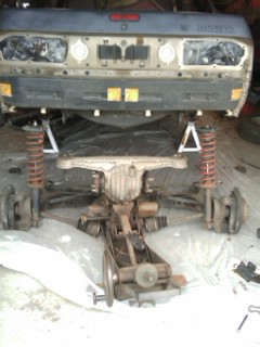 1987 Mazda RX-7 - Vehicle's rear axle and suspension components are disassembled and supported by jack stands and stands.
