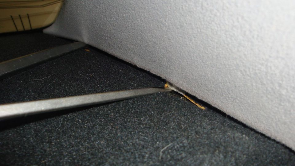 Close-up of a gap between gray headliner trim and dark carpet