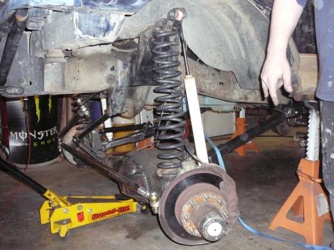 1991 Ford Bronco - The vehicle's suspension is being worked on, with a jack and jack stands supporting it.