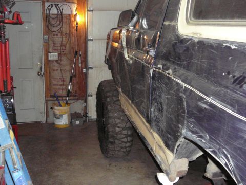 1991 Ford Bronco - This lifted Ford Bronco is parked inside a garage, showing its side profile and large off-road tires.
