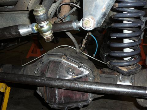 1991 Ford Bronco - Close-up view of a vehicle's rear axle, suspension linkage, and coil spring, likely during a modification or repair.