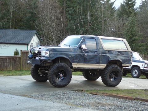 1991 Ford Bronco - Modified 1991 Ford Bronco sits on a driveway with another vehicle visible behind it.