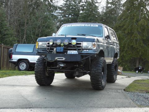 1991 Ford Bronco - This heavily modified Ford Bronco is parked in a driveway with another Bronco in the background.