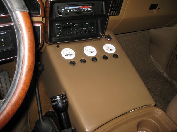 Tan vehicle center console with aftermarket gauges and stereo