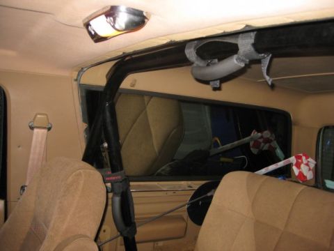 1909 Ford Bronco - Interior view of a vehicle, showing tan seats, a roll cage, and a seatbelt.