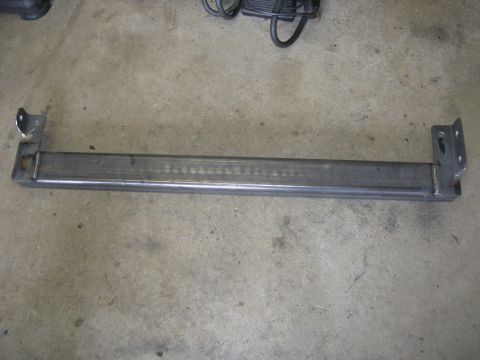1996 Ford Bronco - A metal bar with welded brackets lies on a concrete surface.