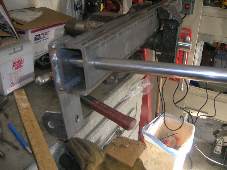 Metal bar held in a vise, with a ruler and gloves nearby