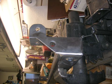 1996 Ford Bronco - A metal bracket is secured in a vise, likely for repair or modification, with workshop items visible behind it the background.