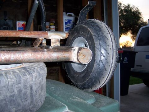 1991 Ford Bronco - The frame of a homemade go-kart is shown with a small tire attached, resting on a green container.
