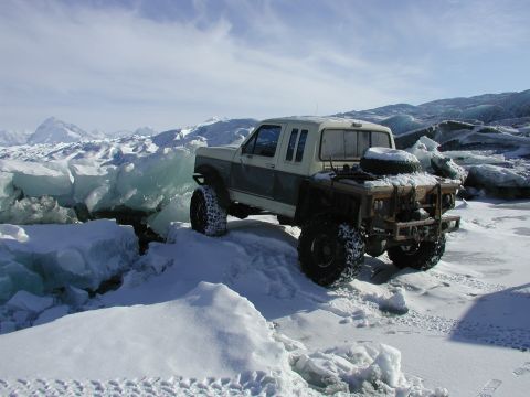 1990 Ford F-250 - A heavily modified 1990 Ford F-250 navigates a treacherous icy terrain under a cloudy sky.
