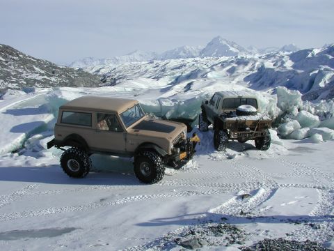 1990 Ford F-250 - Two off-road vehicles are parked on a frozen landscape with icy formations and mountains.