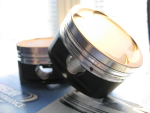 1994 Ford Probe - Close-up view of two high-performance pistons, likely for an engine rebuild or upgrade.