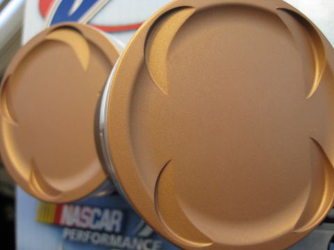 1994 Ford Probe - Close-up of two bronze pistons, with visible NASCAR Performance branding in the background.