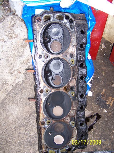 1990 Ford Bronco - A used engine cylinder head is shown, with visible valve seats and combustion chambers.