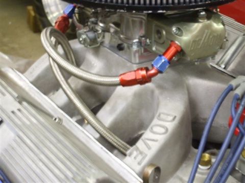 1963 Ford Galaxie - Braided fuel lines connect to a carburetor on an engine intake manifold with "DOVE" lettering visible.