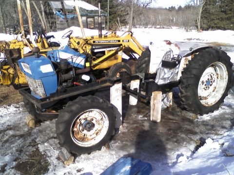 2000 Chevrolet Tahoe - Two tractors are visible in a snowy outdoor setting, one with a blue engine and a yellow loader attachment.