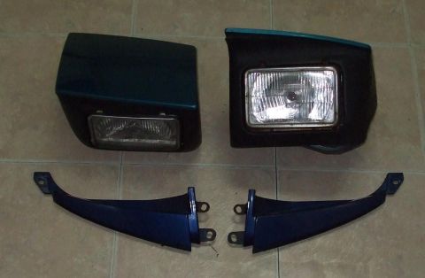 1994 Ford Probe - A pair of headlights and two blue body trim pieces are displayed on a tiled surface.