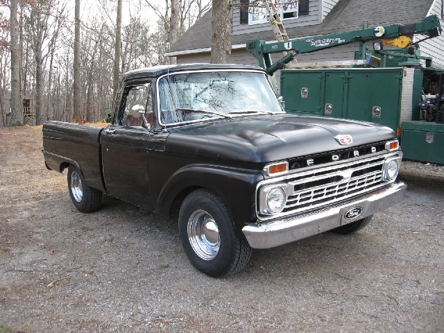 Black 1966 Ford F-100 pickup truck, front 3/4 view, chrome grille with 'FORD' lettering