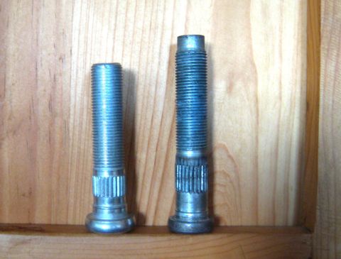 1996 Ford Bronco - Two lug bolts are shown, one shorter than the other, against a wooden surface.