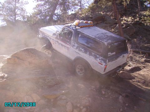 1978 Ford Bronco - A 1978 Ford Bronco navigates a challenging rocky terrain, its tires gripping the uneven surface.