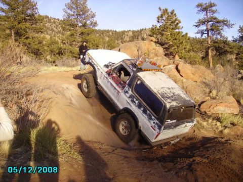 1978 Ford Bronco - Off-road Bronco navigating a challenging trail with rocky terrain and sparse vegetation.