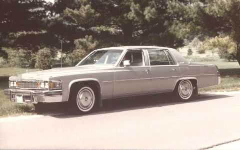 1978 Ford Bronco - This 1977 Cadillac sedan is shown from its left side, parked near trees and grass.