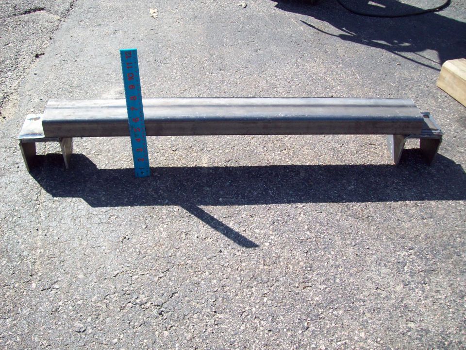 Metal bracket with a blue ruler placed next to it for scale