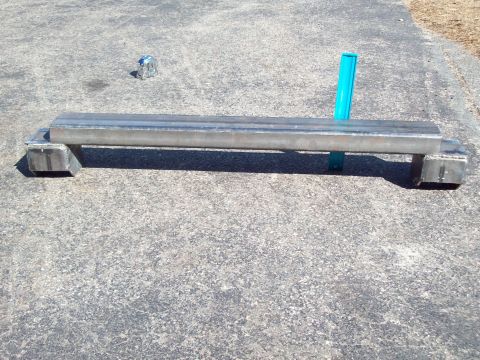 1989 Ford F-150 - A custom metal fabrication part is shown resting on a concrete surface with a tape measure and a blue object.