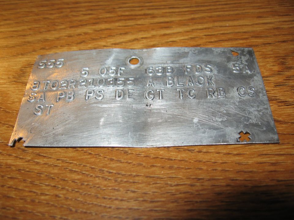 Metal data plate with stamped text including 'A BLACK' and 'GT'