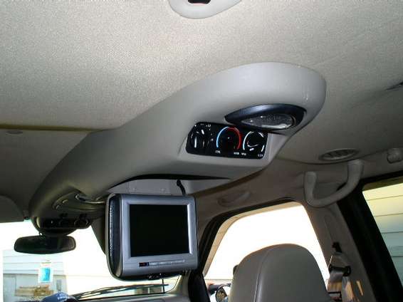 Overhead console with rear climate controls, speaker grille, and flip-down LCD screen in a tan interior