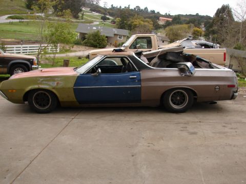 1973 Ford Ranchero - Driver-side profile of a weathered mid-1970s Ford Ranchero coupe-utility in mismatched patchwork paint — faded green front fender, primer-r…
