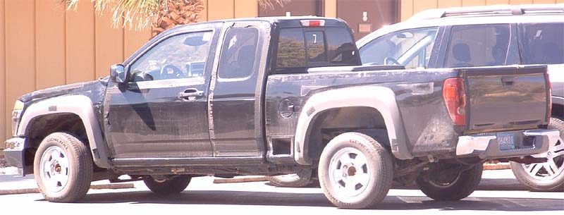 Black Chevrolet Colorado extended-cab pickup with mud splatter parked outdoors