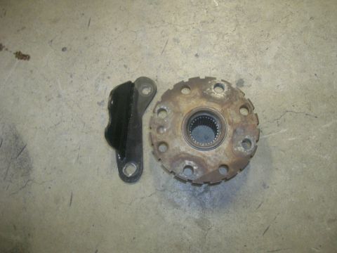 1996 Ford Bronco - A rusty wheel hub with a splined center and a black metal bracket with a rubber insert are shown on a concrete surface.