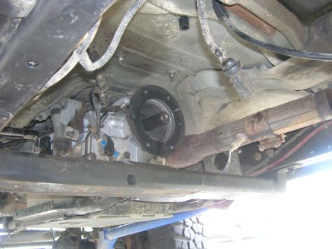 1996 Ford Bronco - The underside of a vehicle shows the transfer case and exhaust system. A circular flange with splines is visible on the transfer case, conn…