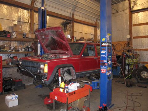 1992 Ford Bronco - Photograph of a red Jeep Cherokee on a lift with its hood up, not a document.