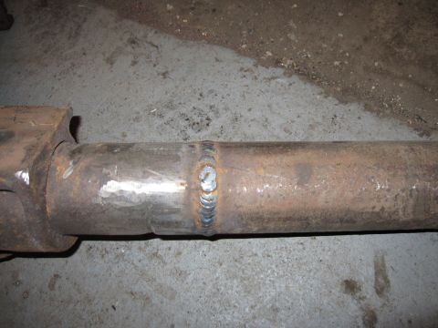 1992 Ford Bronco - Close-up photograph of a welded driveshaft tube on a garage floor, not a document.