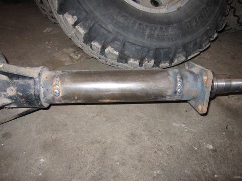 1992 Ford Bronco - Photograph of a welded driveshaft and yoke next to an off-road tire, not a document.