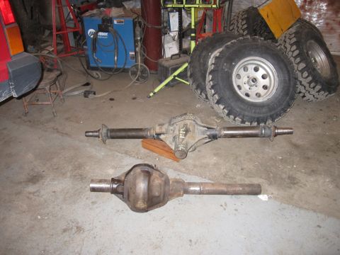 1992 Ford Bronco - Photograph of two axle housings and off-road tires in a workshop, not a document.