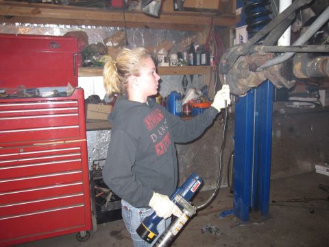 1992 Ford Bronco - Photograph of a person servicing a vehicle suspension component in a shop, not a document.