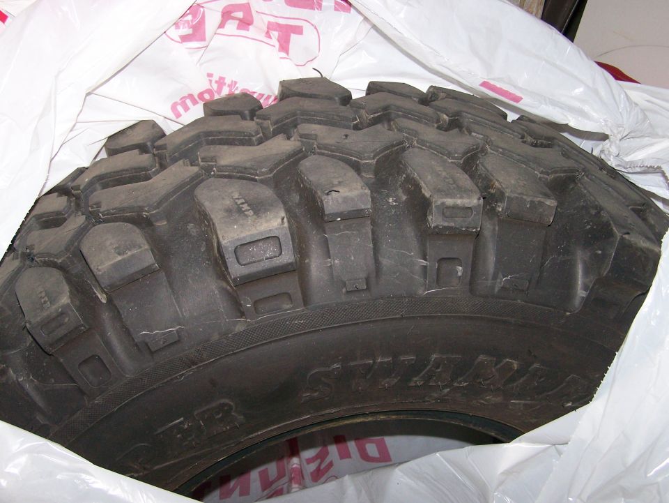 Used mud-terrain tire on white plastic showing tread and sidewall
