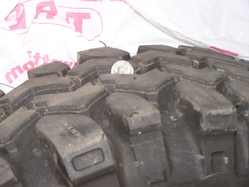 Close-up of deep off-road tire tread with a coin for scale