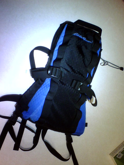 1984 Ford Bronco - A black and blue Eddie Bauer backpack is shown against a white background. The backpack has multiple straps and buckles.