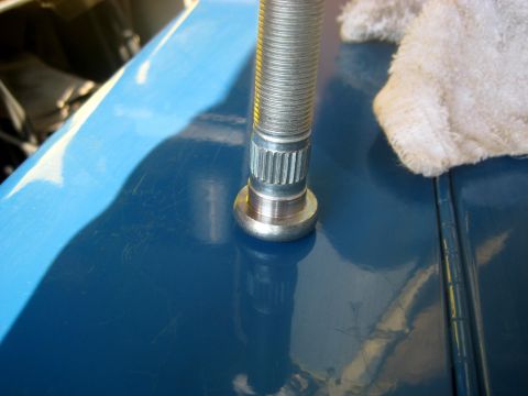 1996 Ford Bronco - A close-up shot shows a silver lug stud protruding from a shiny blue surface, possibly a vehicle body panel. A white cloth is visible to th…