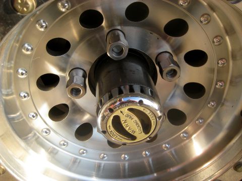 1996 Ford Bronco - A close-up view of a shiny metal wheel hub with a "Warn Locking Hub" mechanism visible. The hub features several lug nuts and a circular pa…