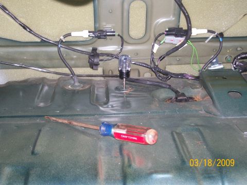 1995 Mercury Grand Marquis - A screwdriver rests on the green metal floor of a vehicle, with wiring harnesses and connectors visible above. The timestamp "03/18/2009" i…