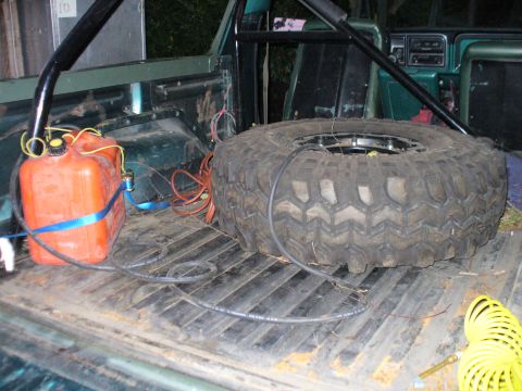 1978 Ford Bronco - The bed of a vintage Ford Bronco shows a large spare tire and an orange gas can secured with straps. A black roll cage is visible behind th…