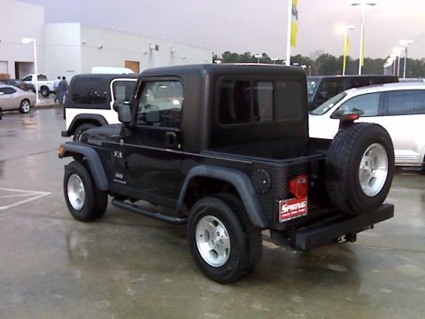 2008 Jeep Wrangler - A black Jeep Wrangler with a hardtop is parked on a wet asphalt lot. The vehicle has a spare tire mounted on the rear and a red license pla…