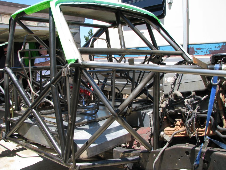 Custom roll cage structure with engine and two men in background