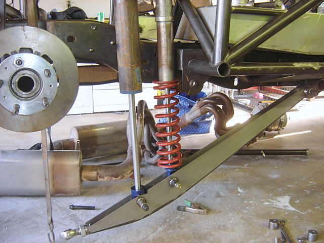 Close-up of custom vehicle suspension with red coilover shock, brake rotor, and exhaust.