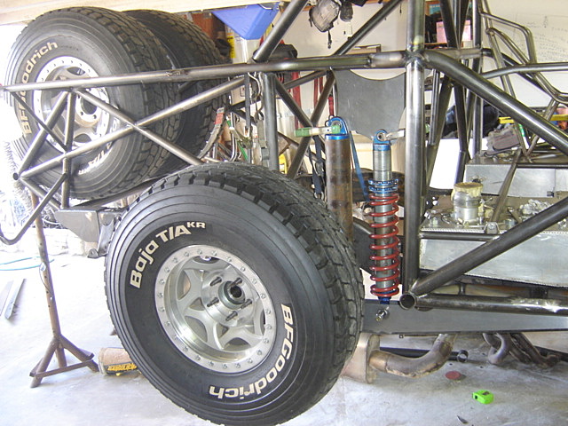 Custom off-road vehicle rear suspension with coilover shock and spare tire.
